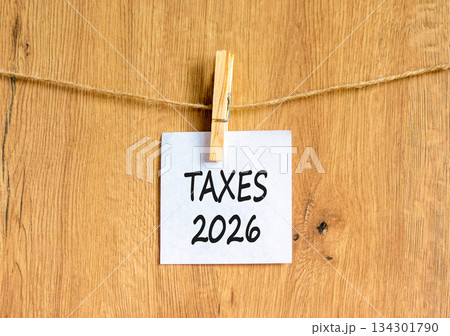 Taxes 2026 new year symbol. Concept words Taxes 2026 on beautiful white paper on wooden clothespin. Beautiful wooden background. Business and taxes 2026 new year concept. Copy space. 134301790