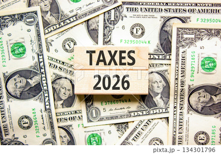 Taxes 2026 new year symbol. Concept words Taxes 2026 on beautiful wooden blocks. Beautiful dollar bills background. Dollar bills. Business and taxes 2026 new year concept. Copy space. 134301796