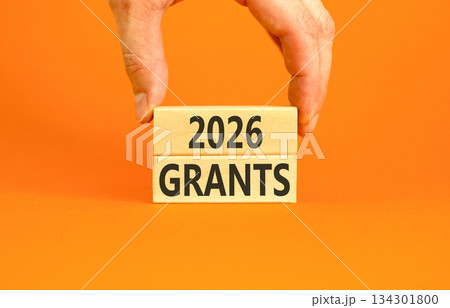 2026 Grants symbol. Concept words 2026 Grants on beautiful wooden blocks. Beautiful orange paper background. Businessman's hand. Business and 2026 grants concept. Copy space. 134301800