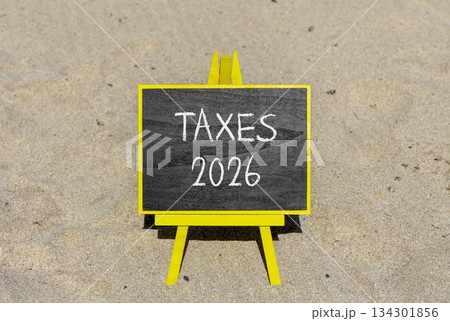 Taxes 2026 new year symbol. Concept words Taxes 2026 on beautiful black blackboard. Beautiful sand beach background. Business and taxes 2026 new year concept. Copy space. 134301856