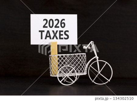 2026 taxes symbol. Concept words 2026 taxes on beautiful white paper on wooden clothespin. Beautiful black background. Beautiful miniature bicycle. Business 2026 taxes new year concept. Copy space. 134302510