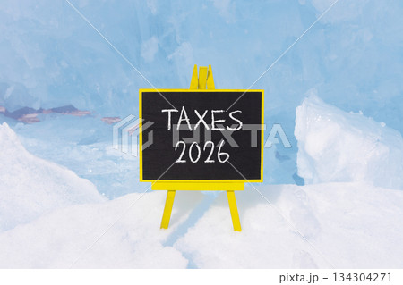 Taxes 2026 new year symbol. Concept words Taxes 2026 on beautiful black blackboard. Beautiful blue lake Baikal ice background. Business and taxes 2026 new year concept. Copy space. Taxes 2026 new year symbol. Concept words Taxes 2026 on beautiful black blackboard. Beautiful blue lake Baikal ice background. Business and taxes 2026 new year concept. Copy space. 134304271