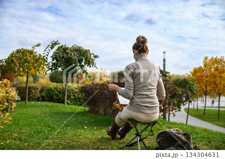 Artist painting outdoors with back view in autumn park. Artist painting outdoors with back view in autumn park. 134304631