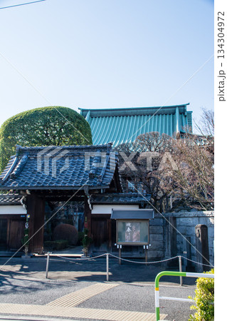 快晴の空の下の冬の枝木に囲まれた大きい緑色の瓦屋根のお寺とお墓群 東京の王子にて 快晴の空の下の冬の枝木に囲まれた大きい緑色の瓦屋根のお寺とお墓群 東京の王子にて 134304972