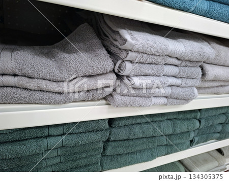 On store shelves, customers can find neatly arranged multicolored cotton towels in various sizes. The towels are stacked neatly for easy viewing and selection. 134305375