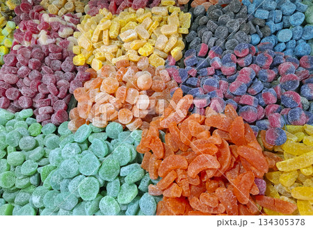 Brightly colored candied marmalade sweets fill the table at a market, attracting attention with their various shapes and sizes. The sweets create a visual treat of sugar and flavor. 134305378