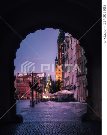Winter City Square Framed by Archway With Christmas Tree, Historic Clock Tower and Cozy Cafe Lights at Dusk In Old Town, Gdansk, Poland Winter City Square Framed by Archway With Christmas Tree, Historic Clock Tower and Cozy Cafe Lights at Dusk In Old Town, Gdansk, Poland 134305988