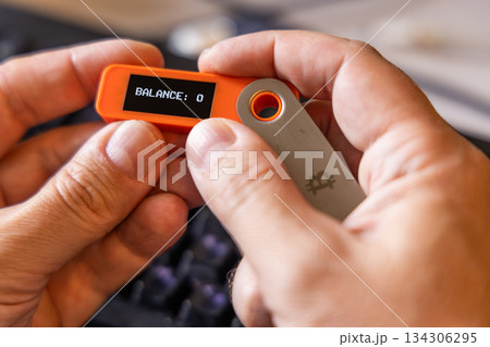 hardware Bitcoin wallet in a hands with message Balance 0 on screen 134306295