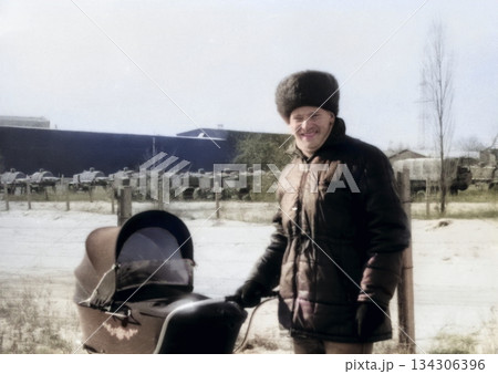 A vintage portrait of happy young father walking with his son in a stroller. Retro photo from 1988. 134306396