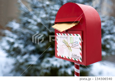 Festive Mailbox. A red mailbox with a letter to Santa in a snowy outdoor setting. Festive Mailbox. A red mailbox with a letter to Santa in a snowy outdoor setting. 134306540