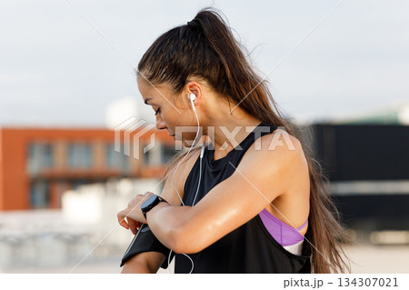 Woman checking her phone on band on her hand during a workout  134307021