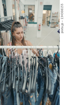 A young woman is shopping for jeans in a trendy retail store that sells fashionable apparel A young woman is shopping for jeans in a trendy retail store that sells fashionable apparel 134308155