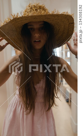 A Young Woman Wearing a Straw Hat Alongside a Lovely Pink Dress Enjoying the Outdoors 134308192