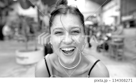 A Joyful Young Woman is Laughing Happily in the Middle of a Bustling Market Scene 134308271
