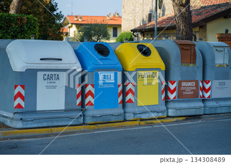 Row of color coded recycling containers for paper, glass, plastic, organic and general waste, showing organized waste separation in a residential area Row of color coded recycling containers for paper, glass, plastic, organic and general waste, showing organized waste separation in a residential area 134308489
