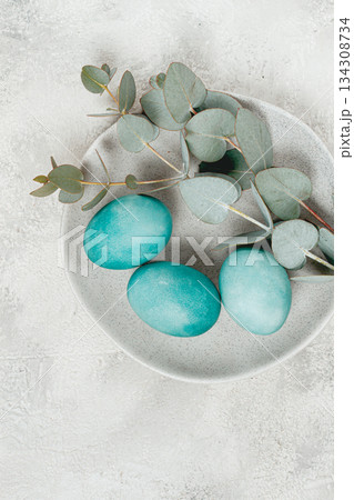 Easter colored eggs, in turquoise tones, on a gray plate, with a branch of eucalyptus, Easter card, top view, no people Easter colored eggs, in turquoise tones, on a gray plate, with a branch of eucalyptus, Easter card, top view, no people 134308734