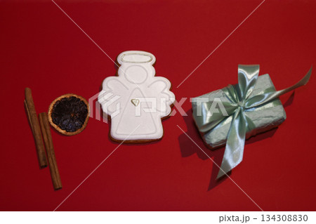Mint gift box with satin ribbon cinnamon sticks and dried orange slice on red background Mint gift box with satin ribbon cinnamon sticks and dried orange slice on red background 134308830