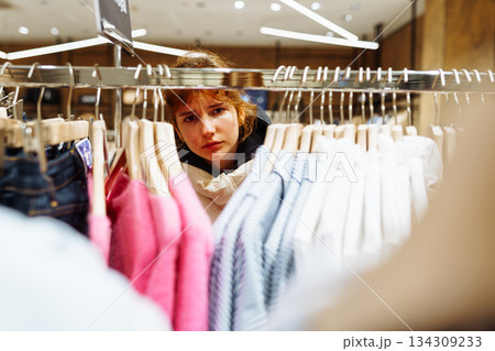 young attractive red-haired woman choosing clothes in boutique 134309233