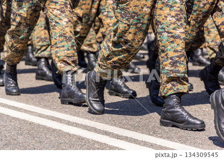 Military personnel marching in formation on paved road during parade Military personnel marching in formation on paved road during parade 134309545