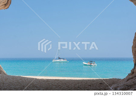 Two boats rest on crystal-clear turquoise water, framed by a natural seaside arch. Soft daylight illuminates the calm sea, creating a relaxed Mediterranean atmosphere ideal for travel themes. Two boats rest on crystal-clear turquoise water, framed by a natural seaside arch. Soft daylight illuminates the calm sea, creating a relaxed Mediterranean atmosphere ideal for travel themes. 134310007