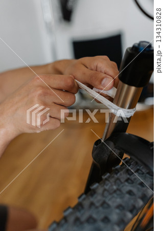 Close-up cropped shot of unrecognizable man wiping cleaning bicycle front fork with clean cloth, maintaining precision and mechanical integrity during maintenance process, close-up. 134310828