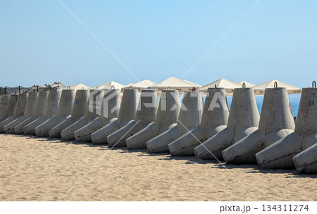 a row of reinforced concrete tetrapod blocks on a sandy beach by the sea a row of reinforced concrete tetrapod blocks on a sandy beach by the sea 134311274