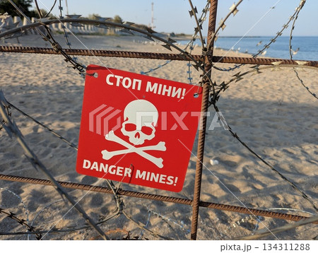 Chernomorsk, Ukraine, July 27, 2025: Warning mine sign placed on a quiet sandy beach. 134311288