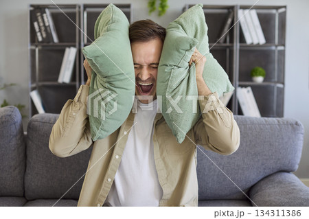 Stressed tenant blocking noise with cushions during neighbor disturbance at home Stressed tenant blocking noise with cushions during neighbor disturbance at home 134311386