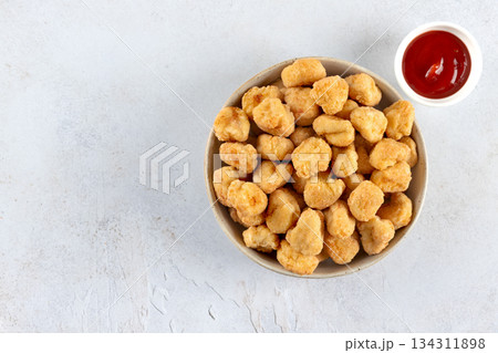 Chicken popcorn in a bowl with ketchup on a white background. Top view. Copy space. Fast food. Chicken popcorn in a bowl with ketchup on a white background. Top view. Copy space. Fast food. 134311898