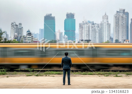 Person in Business Attire Standing Near Moving Train with Cityscape Background 134316823