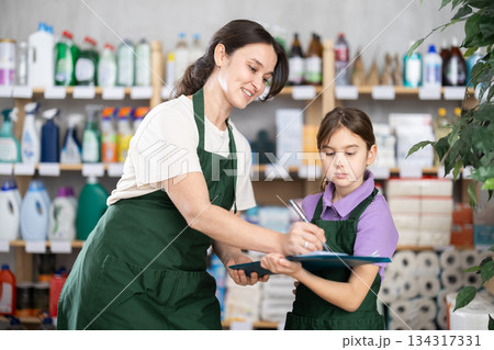 Woman seller and her daughter take inventory in store 134317331