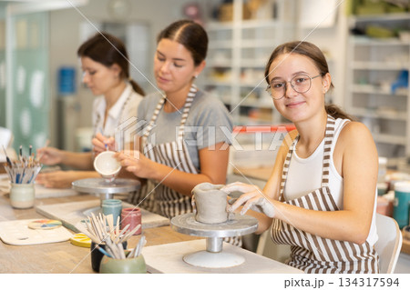 Woman teacher and students sculpt and paint ceramics 134317594