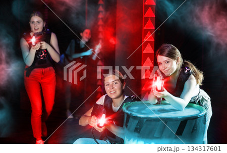 Girls play laser tag, jokingly fight with light weapons Girls play laser tag, jokingly fight with light weapons 134317601