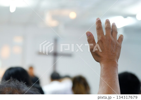 A believer raising a hand in prayer and worship during a church service. The soft focus and added film grain create a classic, emotional atmosphere. Ideal for themes of faith, worship, devotion, and s A believer raising a hand in prayer and worship during a church service. The soft focus and added film grain create a classic, emotional atmosphere. Ideal for themes of faith, worship, devotion, and s 134317679
