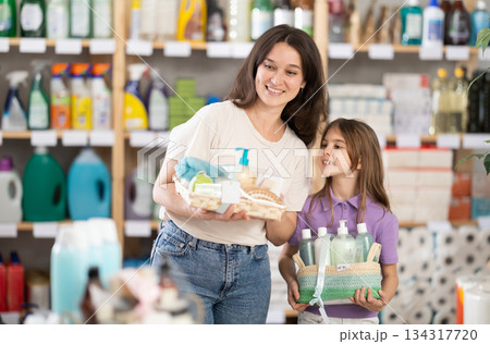Woman with child family selects and studies label present, consist of bathroom cosmetics. 134317720