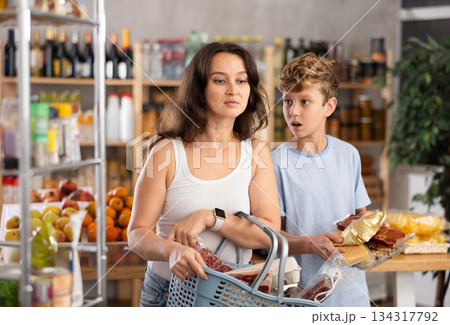 Adolescence boy with mother choose consider snacks in shop 134317792