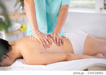 Masseur doing back massage to adult woman 134318002