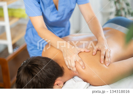 Close up of woman hands of massager woman doing massage to young man in spa salon 134318016