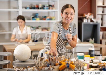 Young woman choosing brush for painting ceramic product Young woman choosing brush for painting ceramic product 134318069