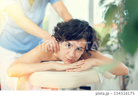 Portrait of young female which is lying on massage table in spa Portrait of young female which is lying on massage table in spa 134318175