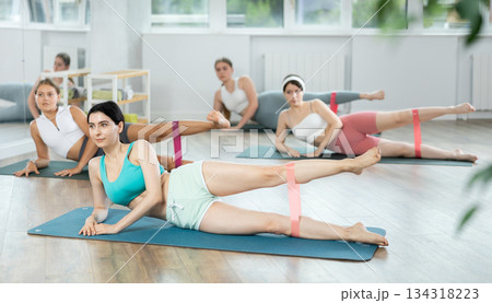 Group of women training leg muscles using resistance bands during Pilates class Group of women training leg muscles using resistance bands during Pilates class 134318223