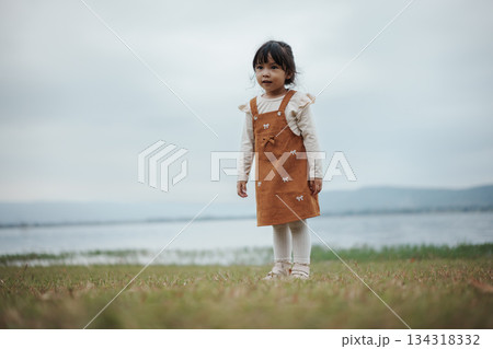 happy toddle girl standing on grass field near the river happy toddle girl standing on grass field near the river 134318332