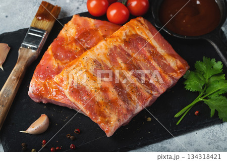 Ready for BBQ raw pork spare ribs with barbecue sauce. Black background. Top view Ready for BBQ raw pork spare ribs with barbecue sauce. Black background. Top view 134318421