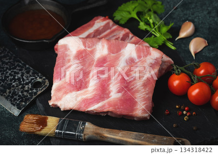 Raw meat. Raw pork ribs from the back with meat on a black background. background image Raw meat. Raw pork ribs from the back with meat on a black background. background image 134318422