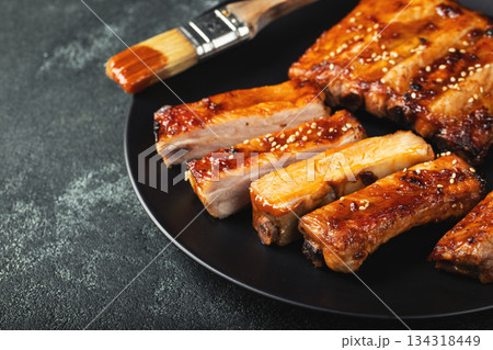 Hot grilled spare ribs from a summer BBQ served on a plate with sauce. Top view. Copy space 134318449