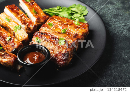 Hot grilled spare ribs from a summer BBQ served on a plate with sauce. Top view. Copy space Hot grilled spare ribs from a summer BBQ served on a plate with sauce. Top view. Copy space 134318472