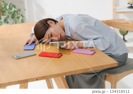 たくさんのスマホに囲まれて落ち込む女性 134318511