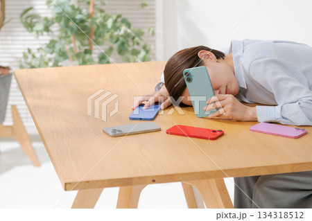 たくさんのスマホに囲まれて落ち込む女性 134318512