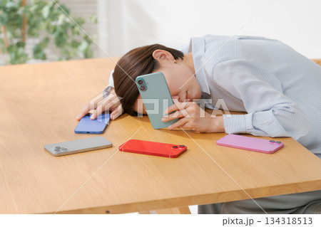 たくさんのスマホに囲まれて落ち込む女性 134318513