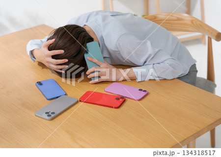 たくさんのスマホに囲まれて落ち込む女性 134318517